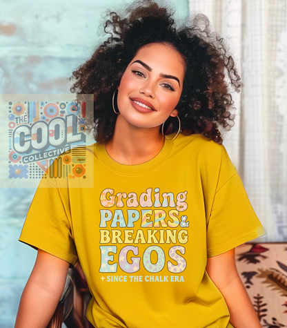Pastel typography teacher t-shirt with the phrase ‘Grading Papers & Breaking Egos — Since the Chalk Era’ in bold retro patterns.”